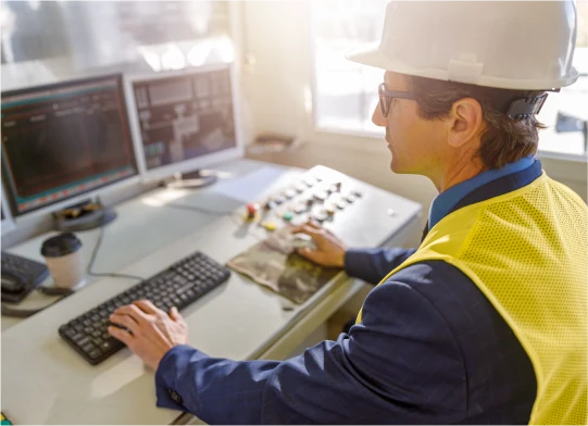 Operador de planta industrial na sala de controle acompanhando as telas de operação